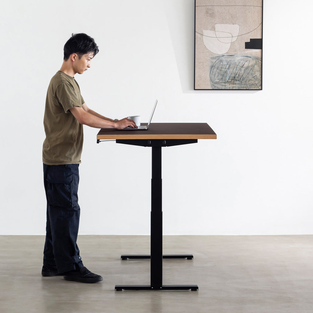 ファニチャーリノリウム素材のMauve天板と、ブラックの電動昇降脚を組み合わせた、デザイン性も機能性もスマートなテーブル（男性使用例）