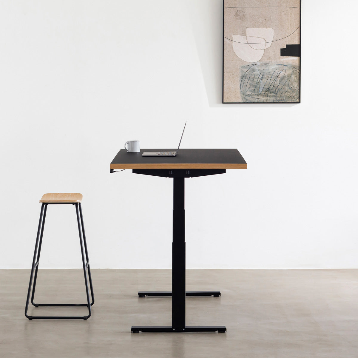 ファニチャーリノリウム素材のNero天板と、ブラックの電動昇降脚を組み合わせた、デザイン性も機能性もスマートなテーブル（スタンディング側面）