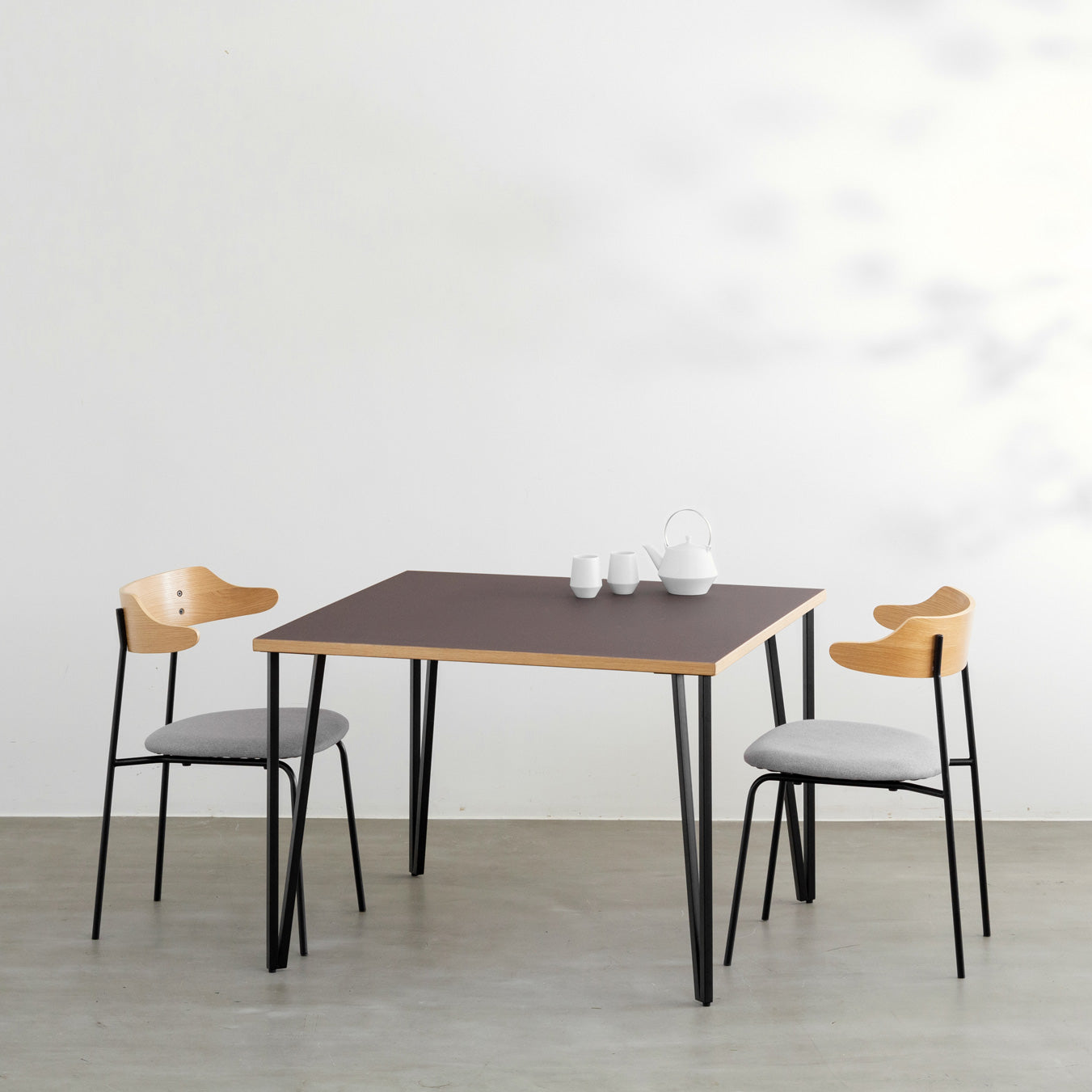 KANADEMONOのリノリウムMauve天板とブラックトライアングルピン4本を組み合わせた一辺100cmスクエア型のカフェテーブル（使用例）