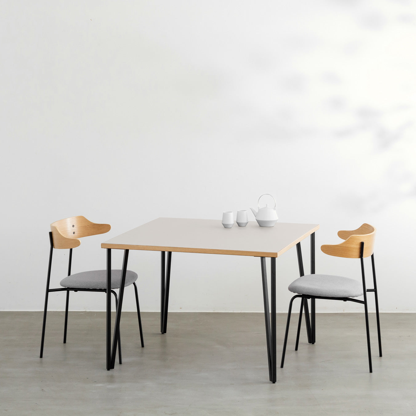 KANADEMONOのリノリウムMashroom天板とブラックトライアングルピン4本を組み合わせた一辺100cmスクエア型のカフェテーブル（使用例）