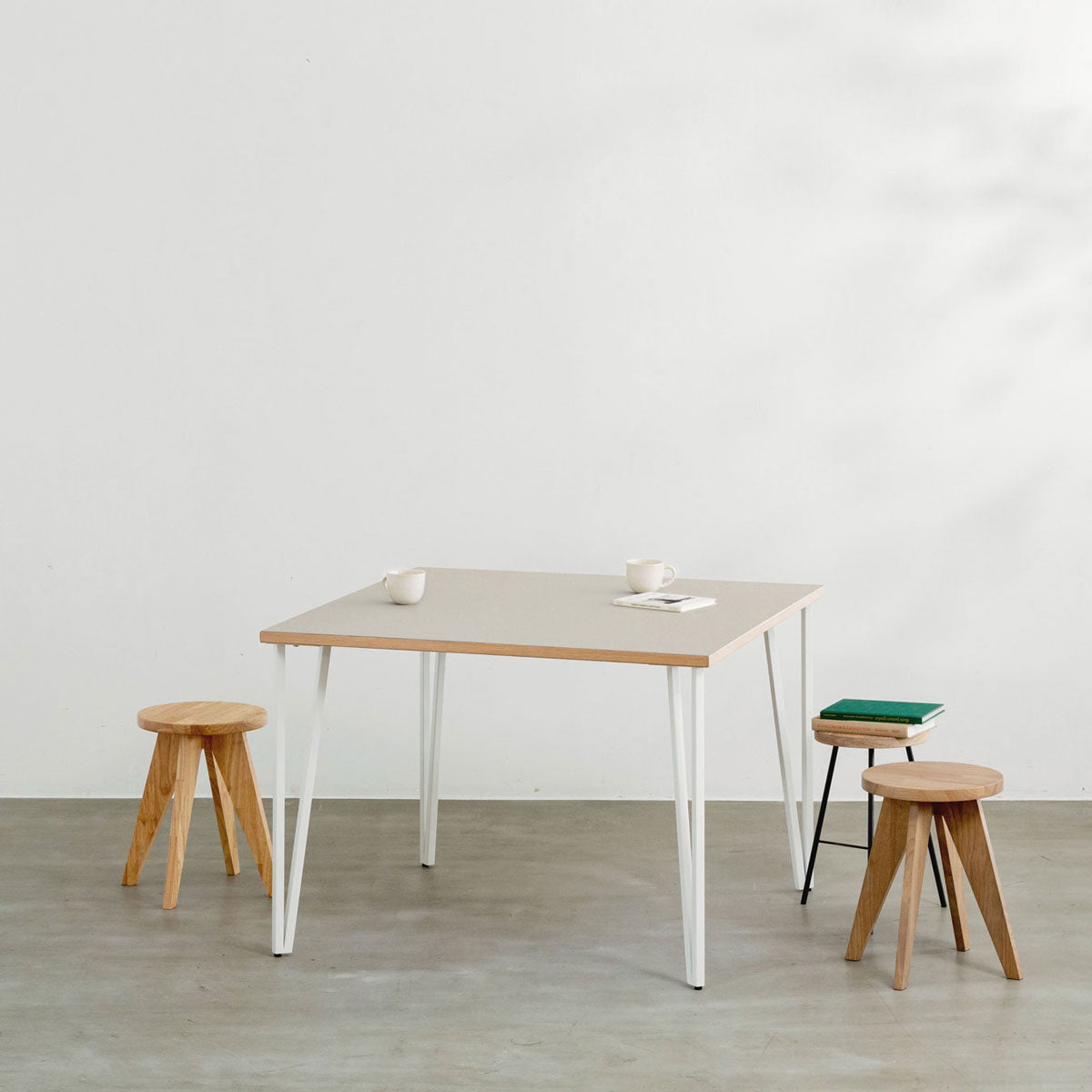 KANADEMONOのリノリウムPebble天板とトライアングルStraightホワイト脚4本を組み合わせた100cmスクエア型のカフェテーブル（使用例）