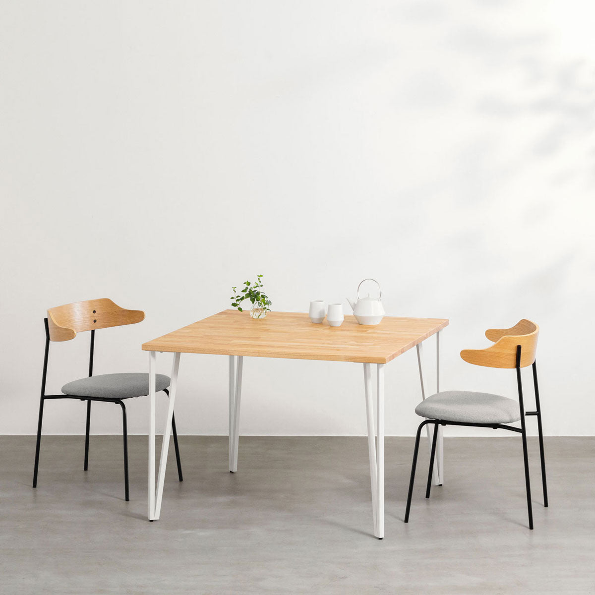 KANADEMONOのラバーウッドナチュラル天板とトライアングルStraightホワイト脚4本を組み合わせた100cmスクエア型のカフェテーブル（使用例）