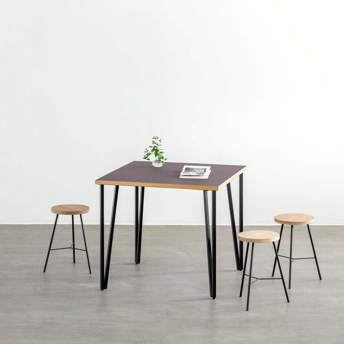 KANADEMONOのリノリウムMauve天板とブラックトライアングルピン4本を組み合わせた一辺80cmスクエア型のカフェテーブル（使用例）