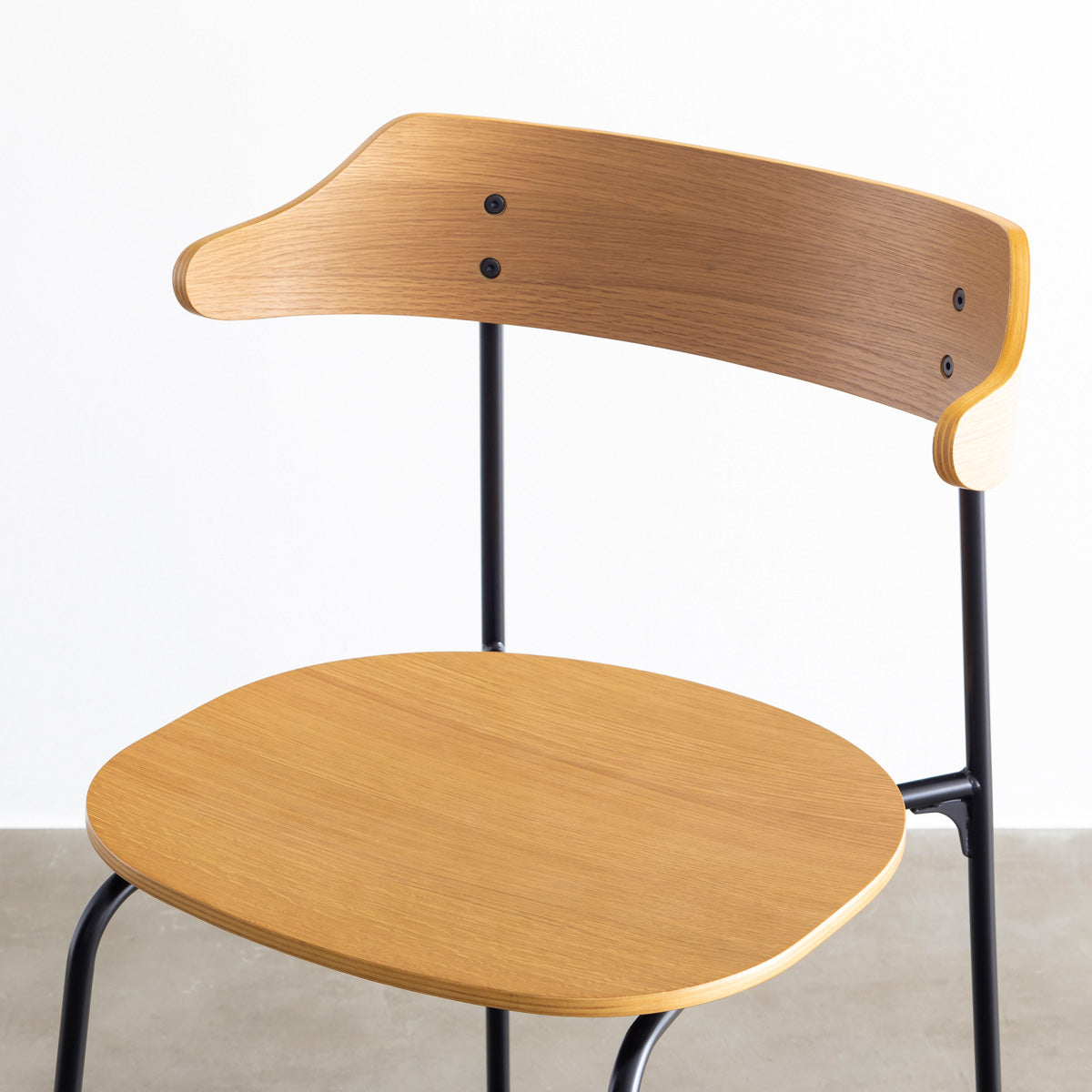 オーク材プライウッドとスチールを組み合わせたナチュラルカラーのハーフアームの板座ダイニングチェア（斜め向き・クローズアップ）