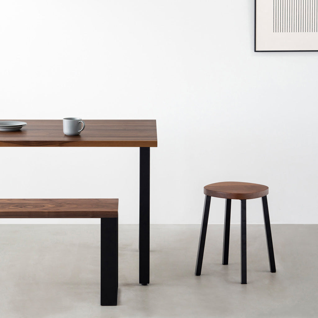 KANADEMONOの無垢ウォルナットSquircle座面とブラックのSlant Bar脚を合わせたシンプルモダンなスツール（使用例）