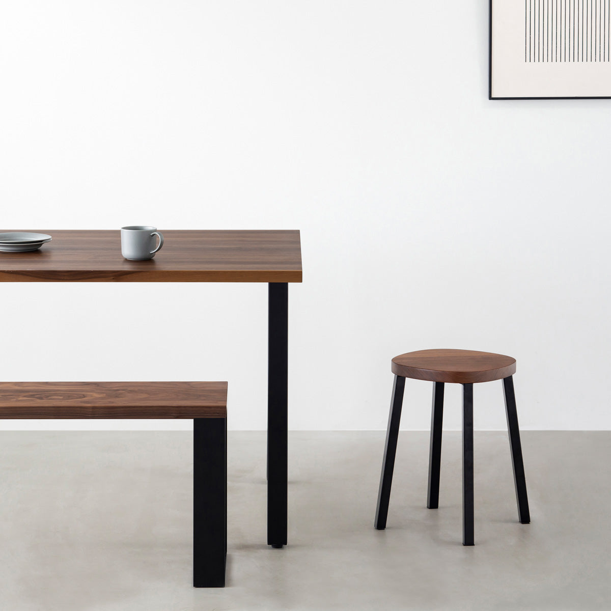 KANADEMONOの無垢ウォルナットSquircle座面とブラックのSlant Bar脚を合わせたシンプルモダンなスツール（使用例）