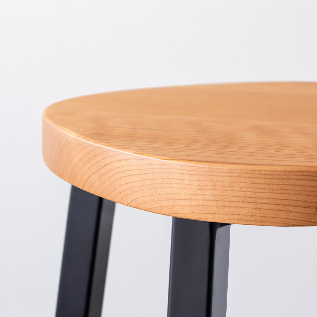 KANADEMONOの無垢ブラックチェリーSquircle座面とブラックのSlant Bar脚を合わせたシンプルモダンなスツール（座面側面）