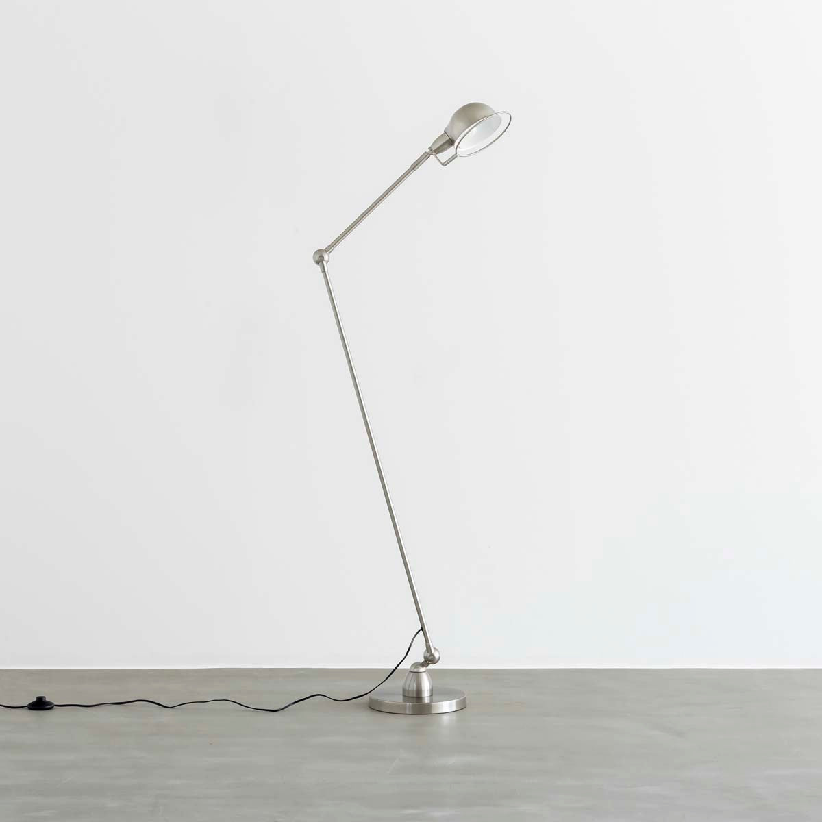 丸みのあるシェードとシャープなシルエットが特徴的なシルバーのフロアランプ