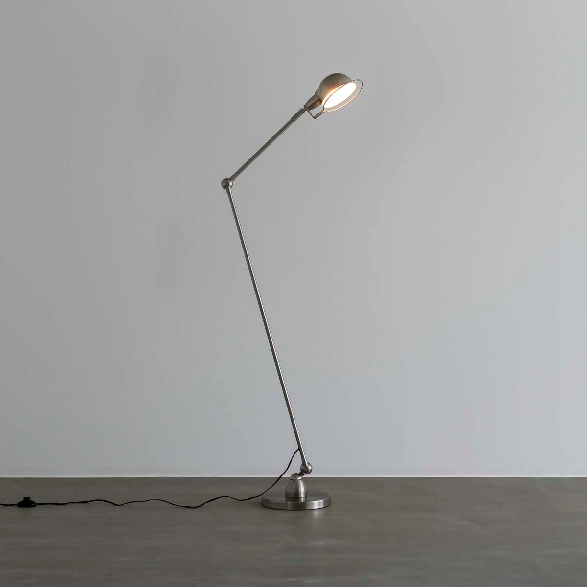 丸みのあるシェードとシャープなシルエットが特徴的なシルバーのフロアランプに明かりを灯して