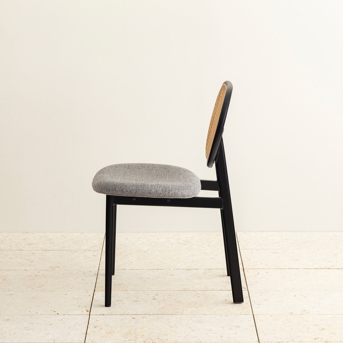 クラシカルなデザインの背もたれにダークグレーのファブリックと黒のスチール脚を組み合わせたレトロモダンなダイニングチェア（横向き）