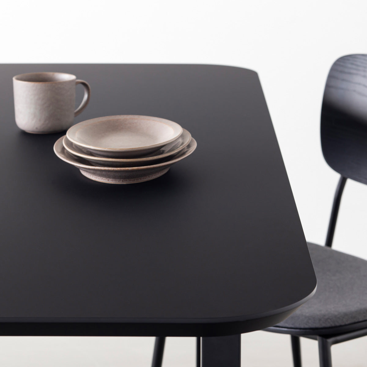 KanademonoのFENIX 天板ブラックにマットブラックのスクエア鉄脚を組み合わせた、優れた性能と美しさを併せもつ新しいテーブル（ダイニング使用例2）