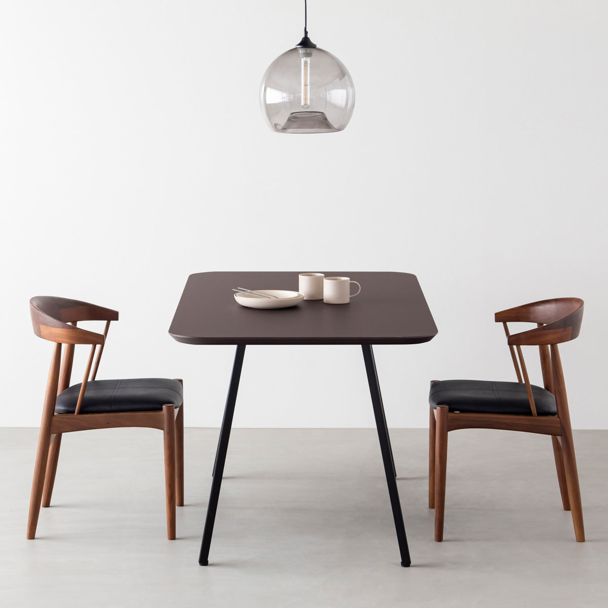 KanademonoのFENIX 天板ブラウンにマットブラックのスリムライン脚を組み合わせた、優れた性能と美しさを併せもつ新しいテーブル（ダイニング使用例）