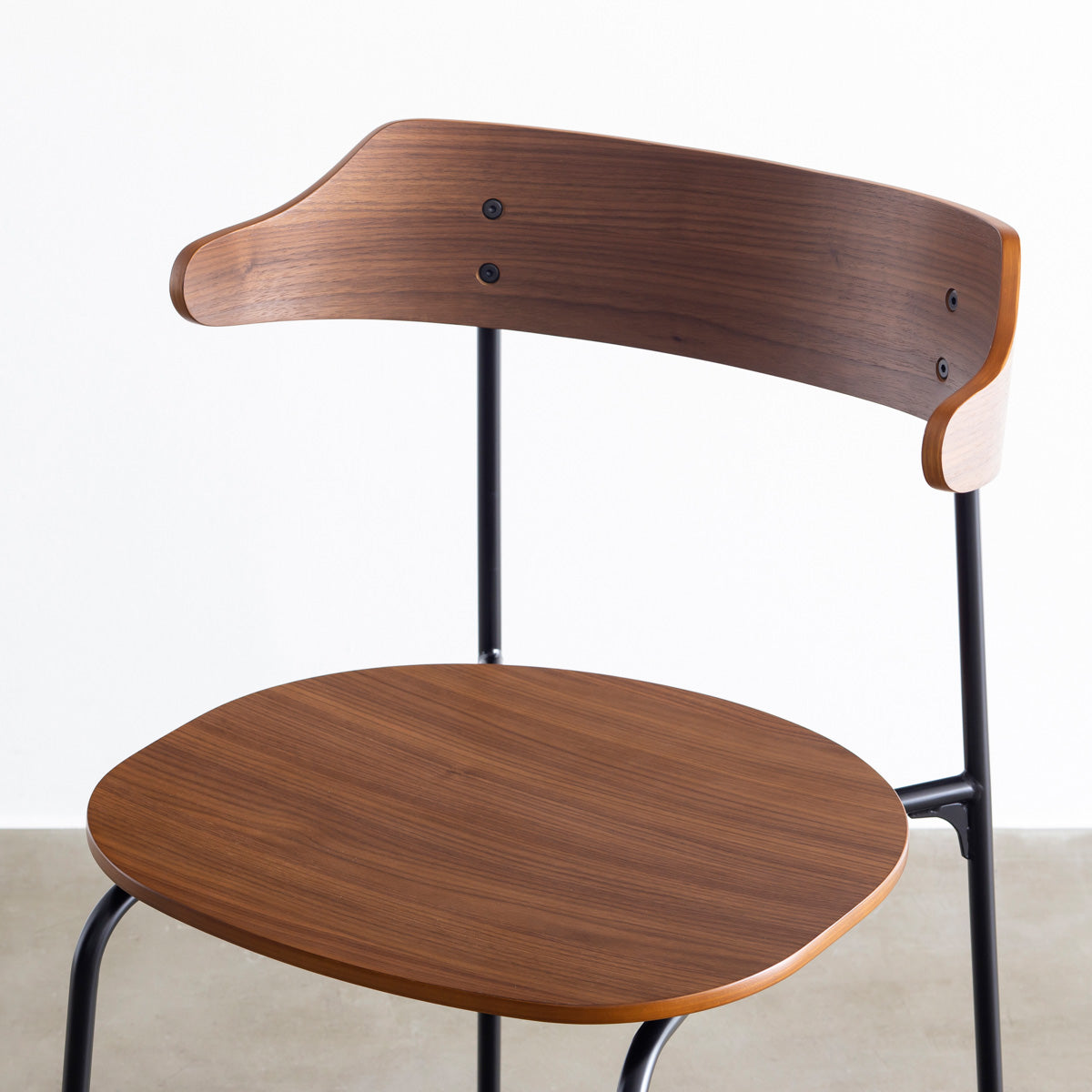 ウォールナット材プライウッドとスチールを組み合わせたブラウンのハーフアームの板座ダイニングチェア（斜め・クローズアップ）